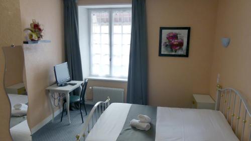 a bedroom with a bed and a desk with a computer at Hôtel Duguesclin in La Haye-Pesnel