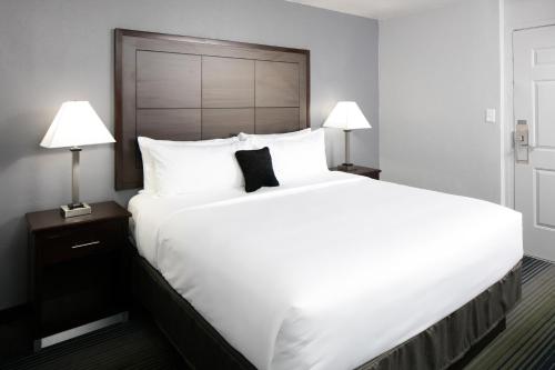 a large white bed in a hotel room with two lamps at Red Lion Inn & Suites Tucson Downtown in Tucson