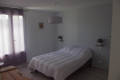 Una cama en una habitación blanca con ventana. en La Maison Oceane, en Dolus d'Oléron