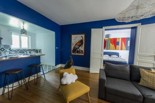 Il comprend un salon avec des murs bleus, un canapé et une cuisine. dans l'établissement Appartement aux remparts des Hospices, à Beaune