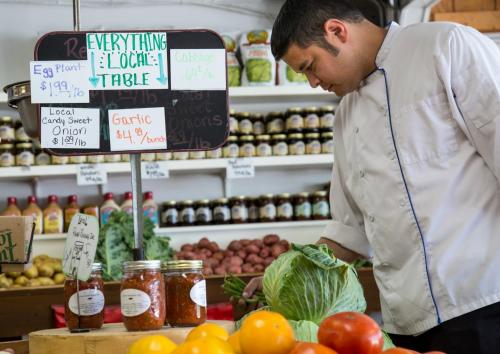 a man standing in a grocery store preparing food at L'Auberge Provencale Inn & Restaurant in Boyce