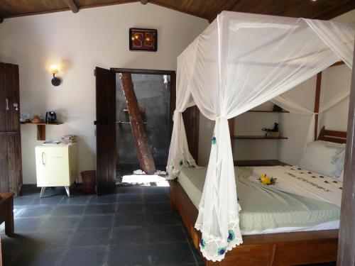 a bedroom with a bed with a mosquito net at Pousada O Refúgio in Jericoacoara