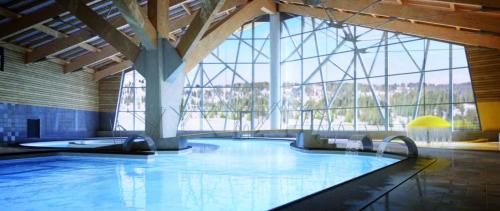 a large swimming pool in a building with a large window at Petit HAUTLIEU in Les Saisies