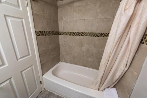 a bathroom with a white tub and a shower curtain at Olympia Lodge in Calgary