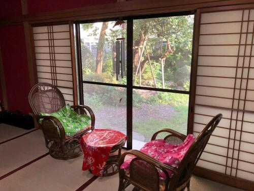 a room with two chairs and a window with a giraffe outside at HappyCloset&WasamonHostel in Kumamoto