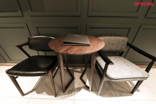 a wooden table with two chairs and a laptop on it at Plum Hotel in Siheung