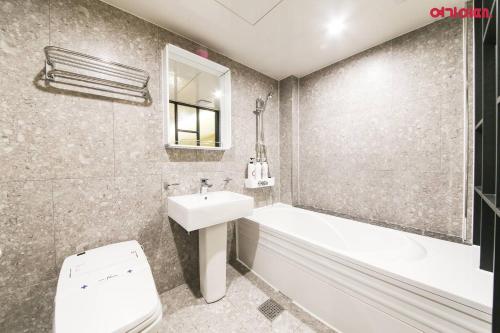 a bathroom with a sink and a tub and a toilet at Plum Hotel in Siheung