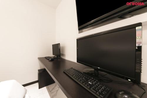 a computer monitor and a keyboard and mouse on a desk at Plum Hotel in Siheung