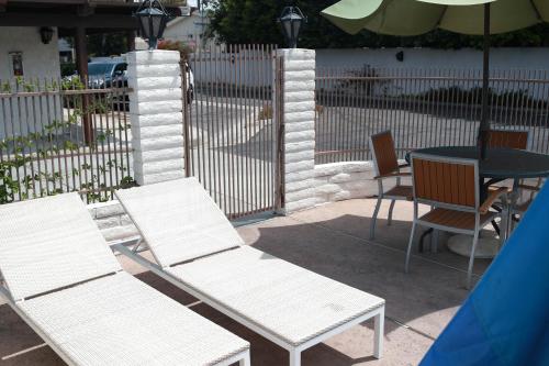three white chairs and a table with an umbrella at Cozy Inn in Costa Mesa