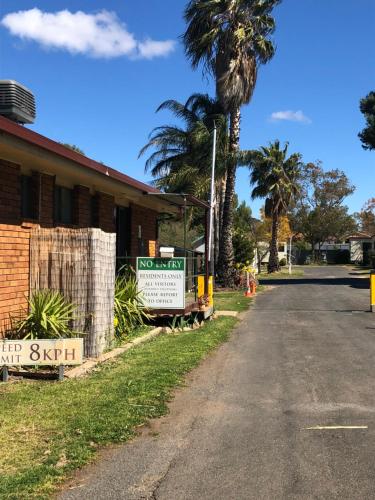 a street sign in front of a house with a palm tree at Parkes Country Cabins in Parkes