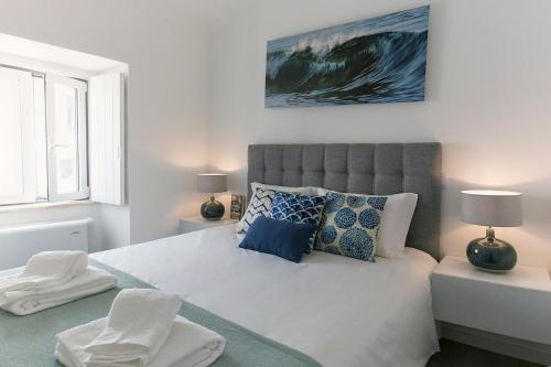 a bedroom with a large bed with blue and white pillows at The Wave House in Baleal