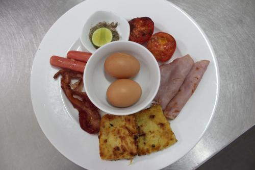 a plate of food with eggs bacon sausage and meat at Central Night Hotel in Siem Reap