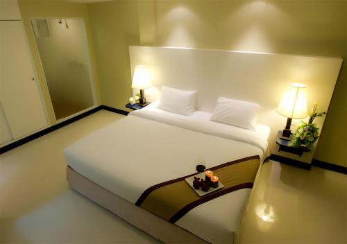 a bedroom with a large white bed with two lamps at Fourteen Again in Pattaya
