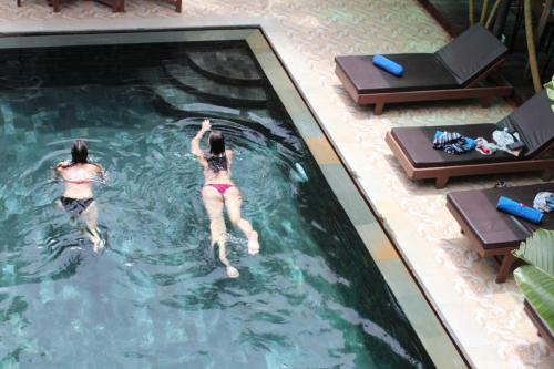 two women are swimming in a swimming pool at Central Night Hotel in Siem Reap