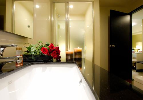 a bathroom with a sink and a vase of red roses at Fourteen Again in Pattaya