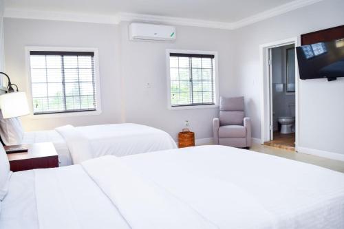 a white room with two beds and a tv at JamGolia Place in Mandeville