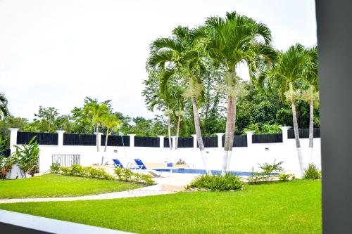 a white fence with palm trees and a swimming pool at JamGolia Place in Mandeville