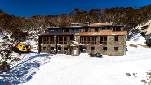 un gran edificio en la nieve con un vehículo amarillo en Boonoona Ski Lodge, en Perisher Valley