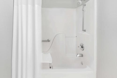 y baño blanco con bañera y ducha. en Super 8 by Wyndham Bay St. Louis, en Bay Saint Louis
