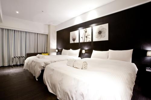 a hotel room with two beds with white sheets at Stay Inn in Taipei