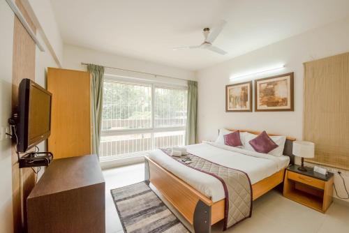 a bedroom with a bed and a tv and a window at The Altruist Business Stays Bellandur-1 in Bengaluru