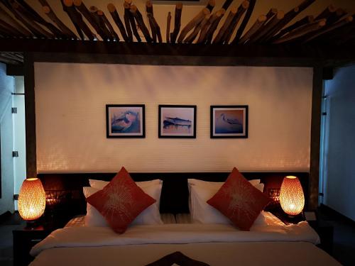 a bedroom with a bed with three pictures on the wall at Nolhi Escape in Nolhivaranfaru
