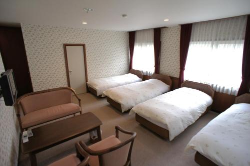 a hotel room with three beds and a chair at Pension Candytuft in Karuizawa