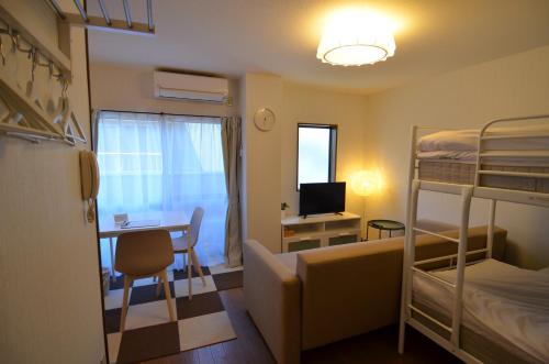 a small room with a desk and bunk beds at Comfort CUBE PHOENIX Beppu (やよいビル) in Beppu