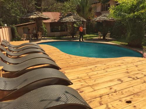 a pool with a wooden deck and a person standing next to it at Outpost Lodge in Arusha