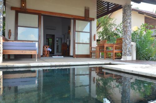 a house with a swimming pool in front of a house at Cocotinos Sekotong Lombok in Sekotong
