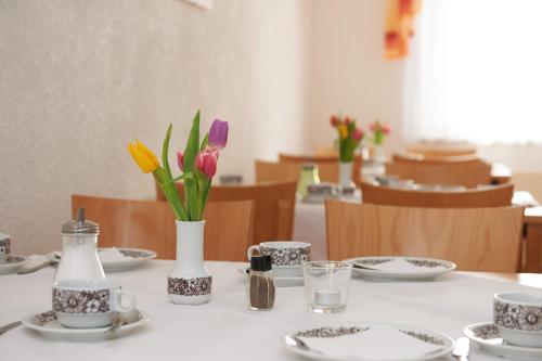 a table with plates and cups and flowers on it at Alpha Apparthotel leipzig-Rötha in Rötha