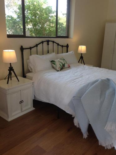a bedroom with a bed with white sheets and two lamps at Port Elliot rural retreat in Port Elliot
