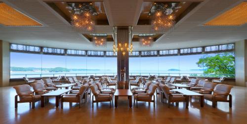 a dining room with tables and chairs and large windows at Minami Sanriku Hotel kanyo in Shizukawa