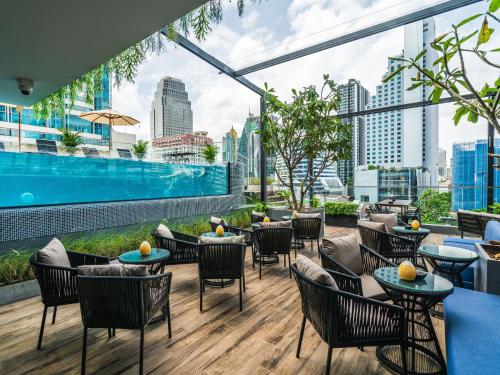 a rooftop patio with tables and chairs and a pool at Tastoria Collection Sukhumvit in Bangkok