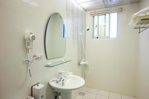 ein weißes Badezimmer mit Waschbecken und Spiegel in der Unterkunft Taitung Holidays B&B in Taitung