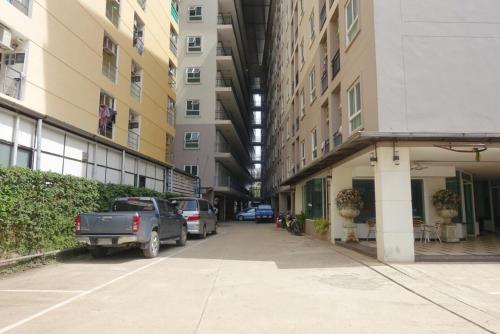 a street with cars parked next to tall buildings at Fenix in Pathum Thani