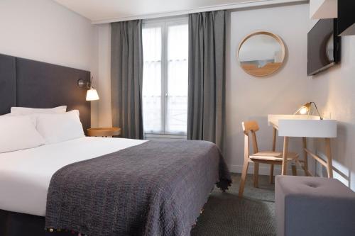 パリにあるホテル デエスパーニュのベッドとデスクが備わるホテルルームです。