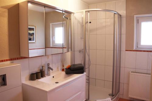 La salle de bains est pourvue d'une douche, d'un lavabo et d'un miroir. dans l'établissement Ferienwohnung Melanie, à Hart im Zillertal