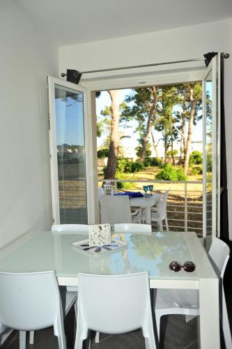 a white dining room with a glass table and white chairs at MARIMAR - Apartments OTRANTO in Otranto