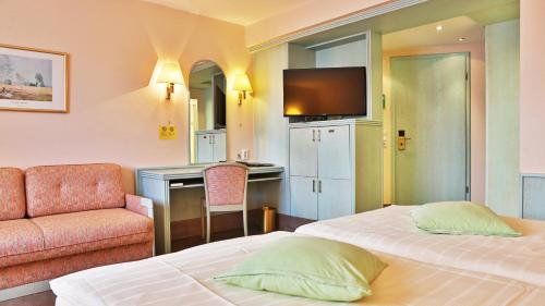 a hotel room with two beds and a television at Hotel Zum Löwen in Mörfelden-Walldorf