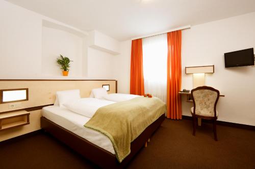
a hotel room with a bed, chair, and nightstand at Hotel Goldene Krone Innsbruck in Innsbruck
