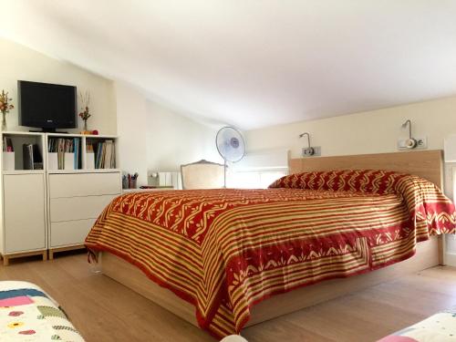 1 dormitorio con 1 cama con manta roja y amarilla en El Corral De La Simona, en Villalmanzo