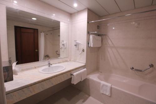 a bathroom with a sink and a tub and a mirror at Suite Hotel Jardins Da Ajuda in Funchal