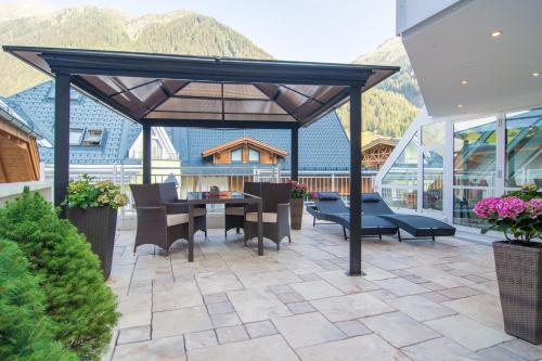 a patio area with chairs, tables, and tables with umbrellas at Alphotel Garni Salner in Ischgl