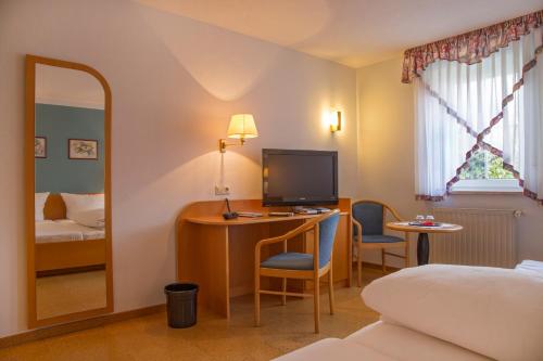 a hotel room with a bed and a desk with a television at Hotel zur Linde in Gädheim