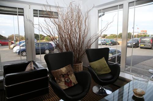 a room with two chairs and a table and windows at Inn On The Prom At The Fernlea Hotel in Lytham St Annes