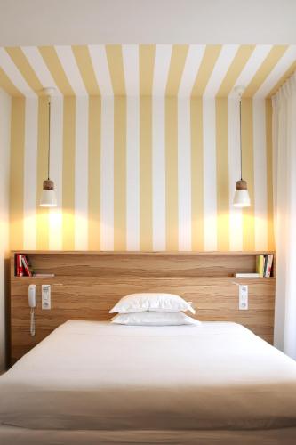 a bedroom with a bed with a striped wall at Hôtel et Apparts Marin in Laval