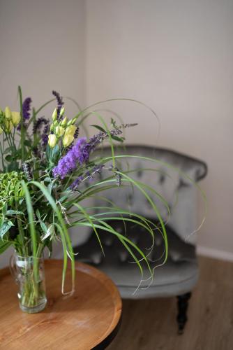 a vase of flowers on a table next to a chair at Hotel Clemar in Znojmo