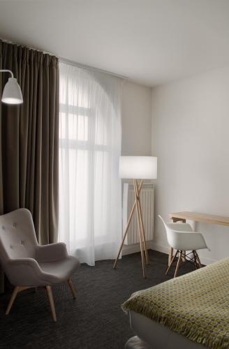 a bedroom with a bed and a table and a chair at Hôtel et Apparts Marin in Laval