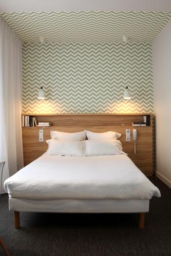 a bedroom with a large white bed and a wall at Hôtel et Apparts Marin in Laval